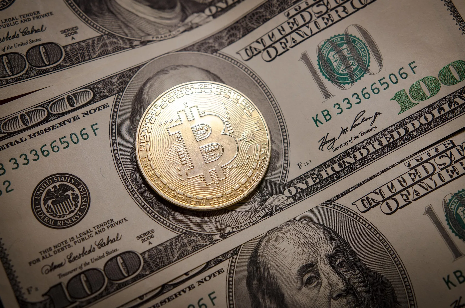 Bitcoin coin resting on US dollar bills