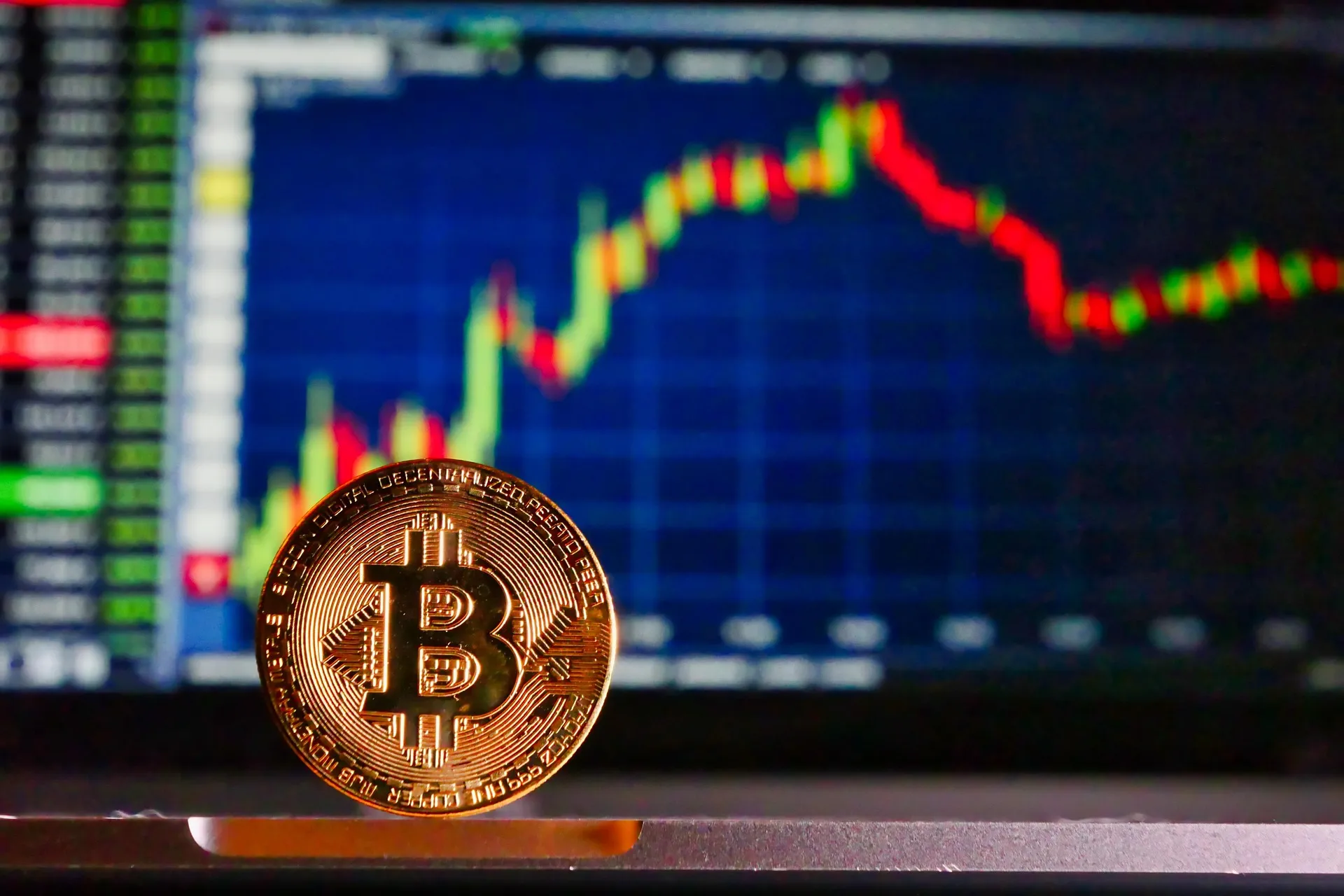 Bitcoin coin in front of a candlestick trading chart