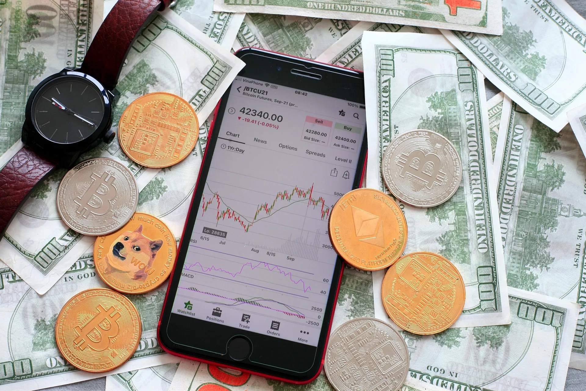 Crypto coins and a phone showing a price chart on dollar bills